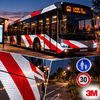Bus de ville habillé de bandes de balisage rétroréfléchissantes 3M Scotchlite 7600 rouge et blanc et panneaux de signalisation urbaine de nuit
