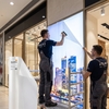 Poseurs appliquant le film de rétroprojection ASLAN RP 35 sur une baie vitrée commerciale pour écran d'affichage dynamique