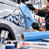Retrait du film pochoir bleu Avery Dennison SignMask sur carrosserie de véhicule révélant un décor peint aux contours nets sur surface incurvée