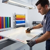 Technicien appliquant le film rétroréfléchissant omnidirectionnel Avery T-6500-A HIP à la raclette sur un panneau en aluminium
