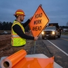 Agent de voirie installant un panneau de chantier orange rétroréfléchissant Avery T6500 pour signalisation temporaire