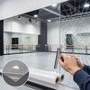 Pose d'un film de protection au dos d'un miroir de studio de danse étoilé par un impact et retenu par le film Reflectiv DOS 060